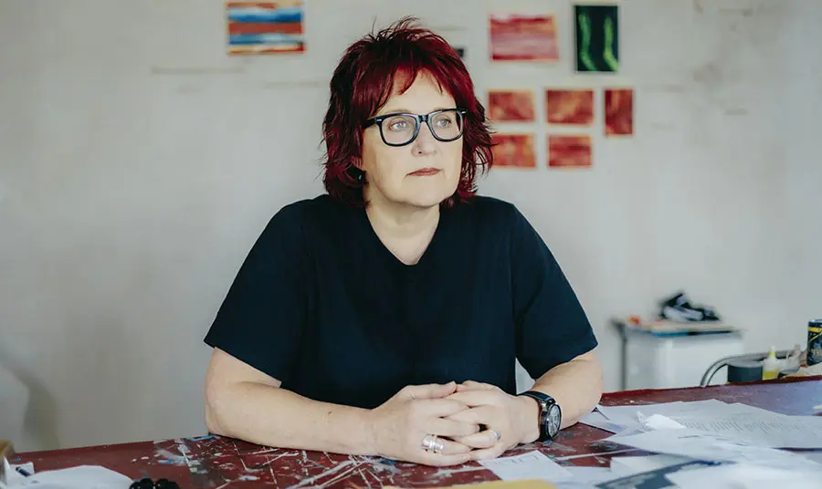 Heather Fleming sits at a table in an artist's studio
