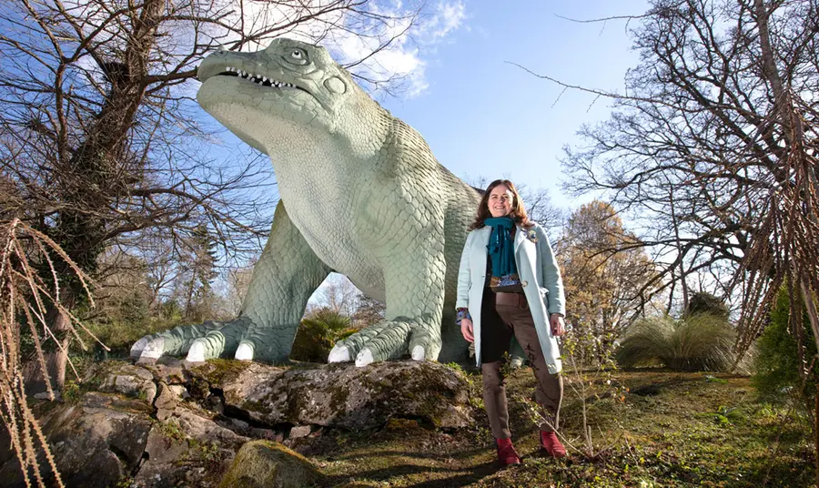 Eilish McGuinness standing in front of one of the Crystal Palace Park dinosaurs