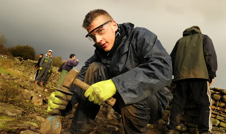 A young person getting involved with dry stone walling