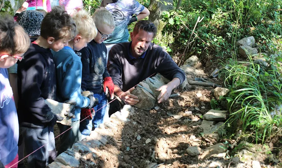 A person demonstrating to a group of children how to properly build a border to a garden. Credit: Golden Tree