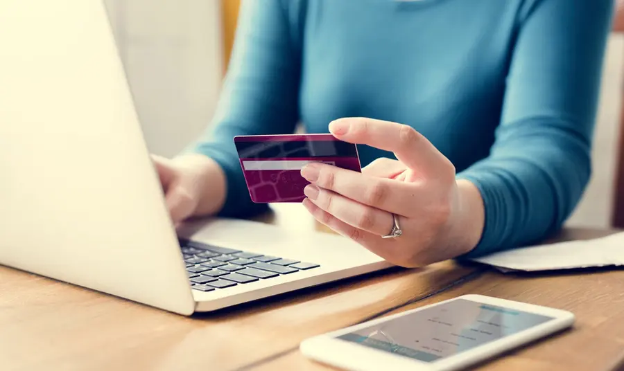 Person using laptop whilst holding bank card