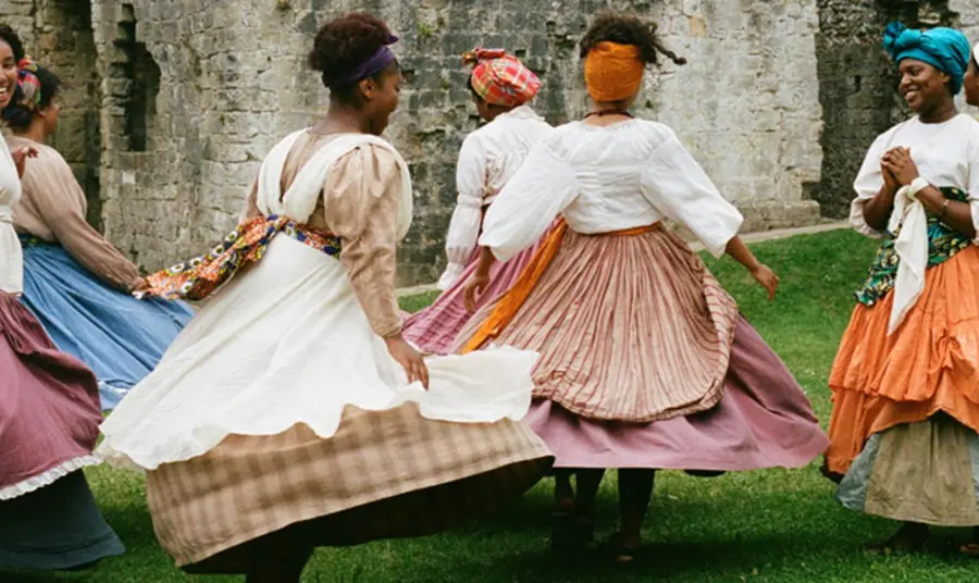 A group of women in period dress dancing outside Porchester Castle.