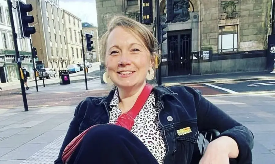 Karen reclines in a chair, smiling, on an Edinburgh street.