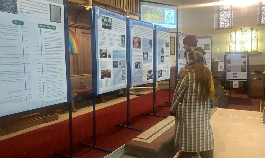 Learning more about the church's history. Two people read information about the church's history from temporary displays.