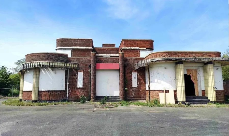 The Iron Duke, before restoration. The facade of the Iron Duke as it stands today, with the curved arc deco windows boarded up and signs of decay.