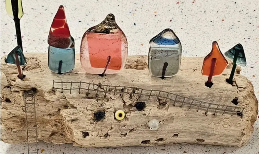 Greener Glass Exhibition, Stourbridge Museum Small colourful houses made of glass are mounted onto a piece of driftwood