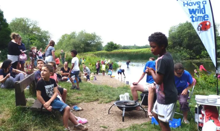 A group of children and adults doing outdoor activities by a river