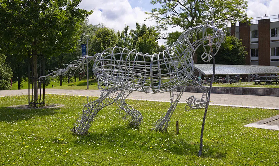 A statue of a horse made from steel wire on a lawn