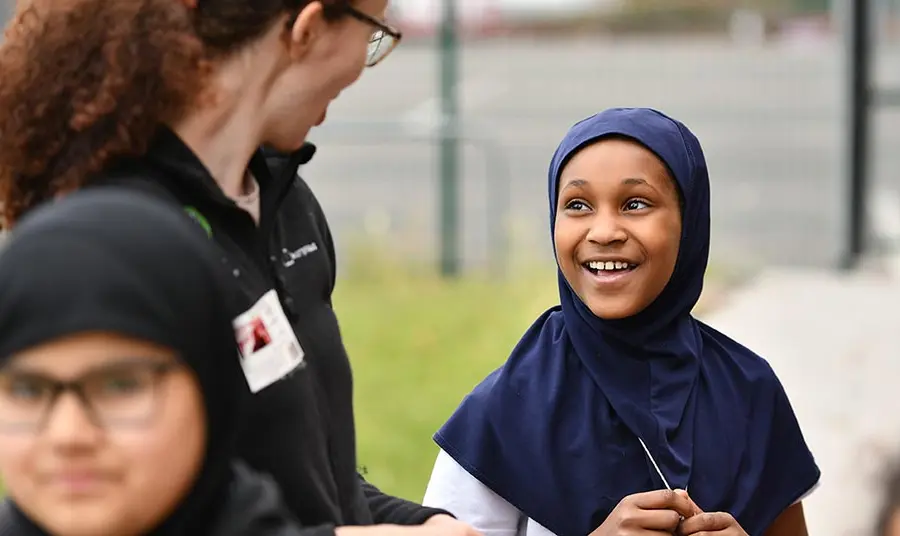 An adult talks to a child wearing a head scarf.