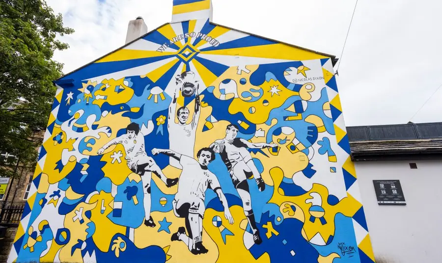 A mural celebrating Leeds United. A mural covers the end wall of a terrace house, depicting scenes from the history of Leeds United football club.