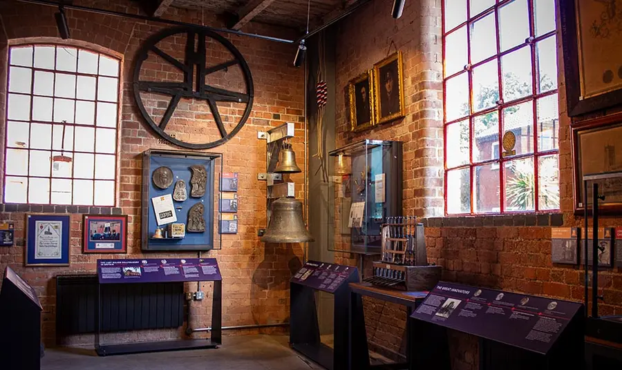 The interior of a bell museum with bells, bell frame and images hung on the walls and panels explaining them