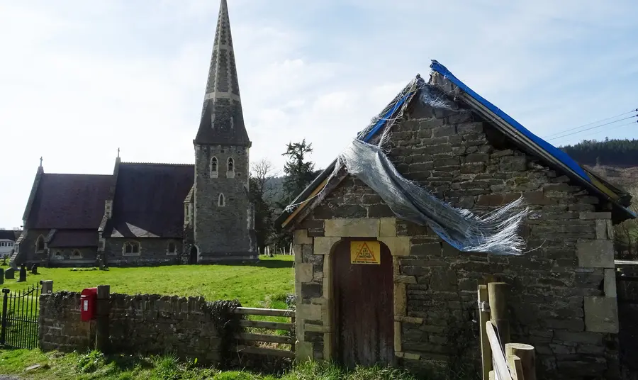 Tŷ’r Meirw Bochrwyd gydag Eglwys Sant Cynog yn y cefndir 