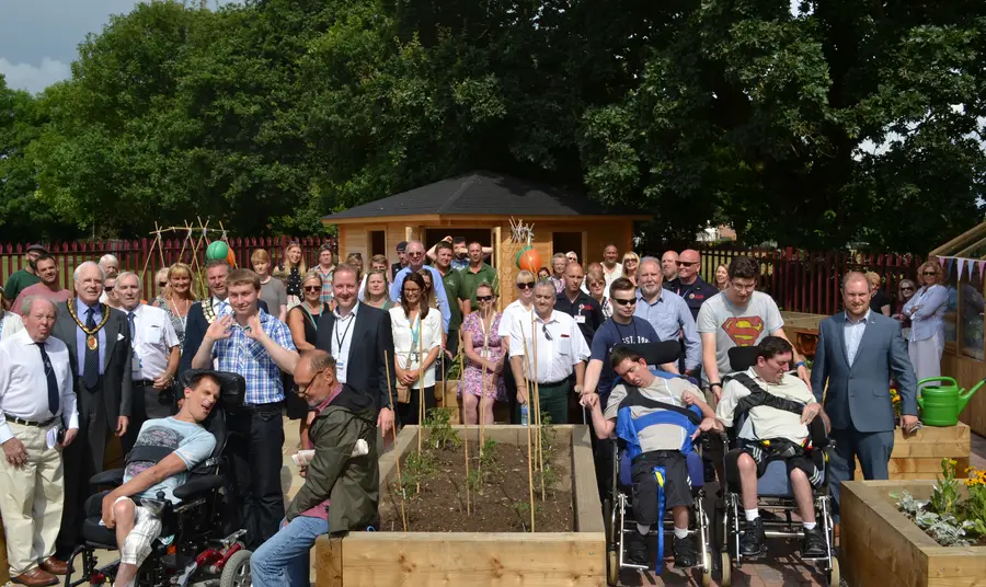 People gather around the raised beds in the community garden