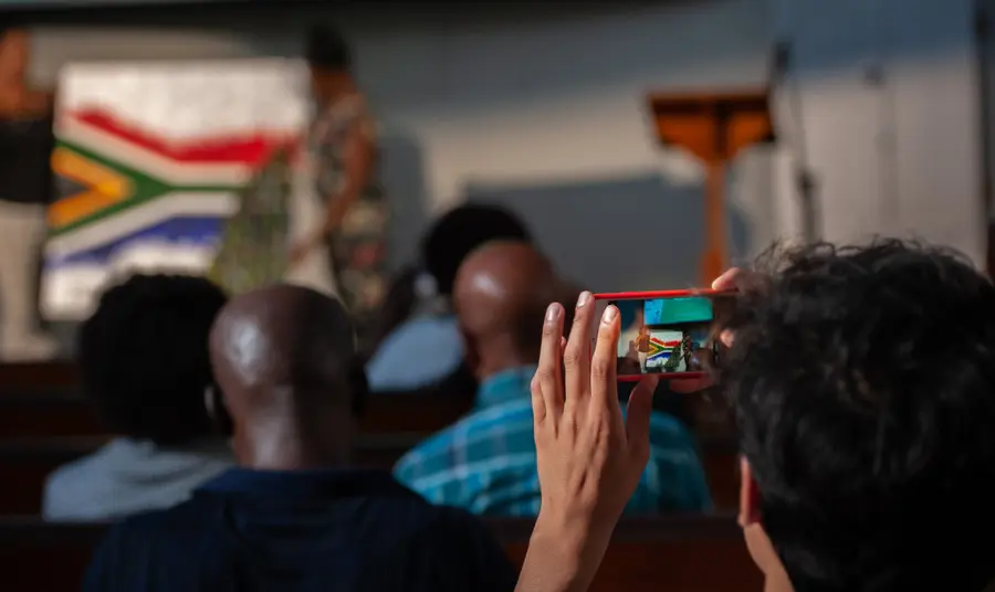 Person taking a picture of the South African flag on a phone camera at The Anti-Apartheid Legacy: Centre of Memory and Learning event