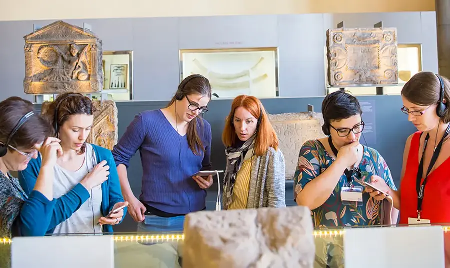 People at a museum engaging with the exhibits using handheld digital devices