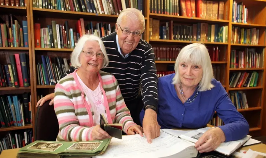 Evaluation guidance Three people smiling whilst pointing at a book