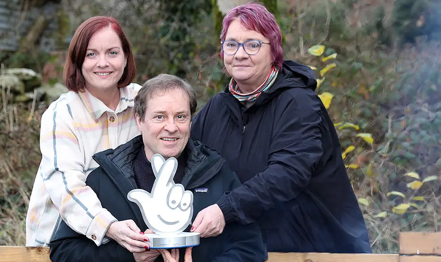 Three people hold an award