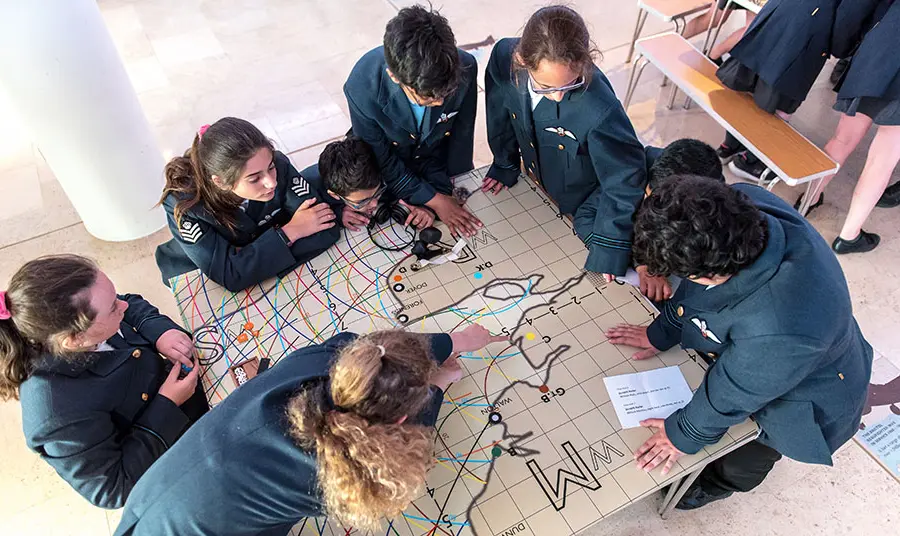 children gather round map of England