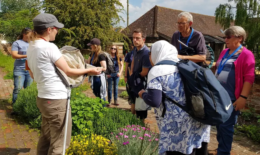 People standing in a garden, watching a speaker talk about bumblebees
