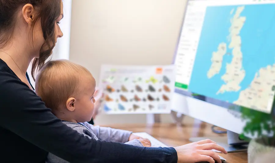 Adult and baby in front of computer showing map of UK