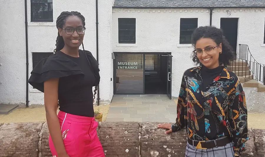 Two people smiling and standing in front of a museum entrance