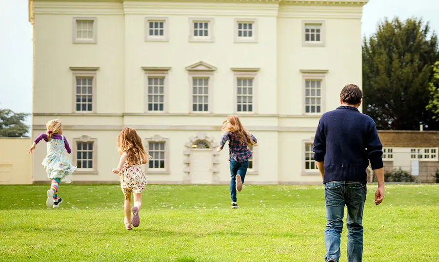 Three children and one adult approach historic house