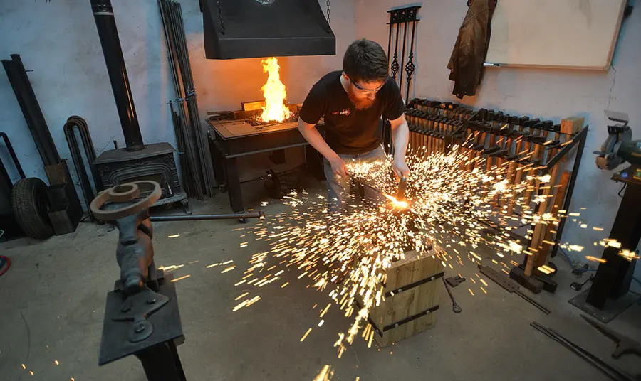 A blacksmith hitting metal, surrounded by a spray of sparks