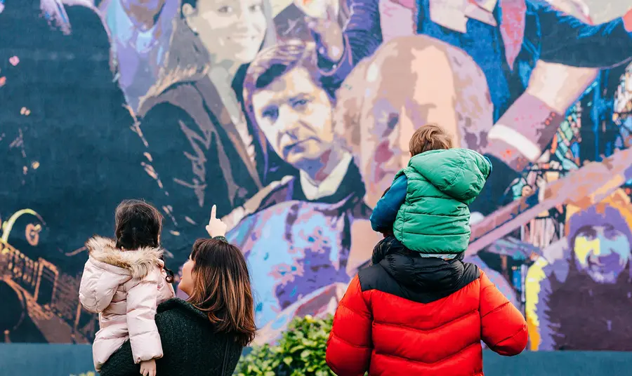 Two adults and two children looking at a wall mural