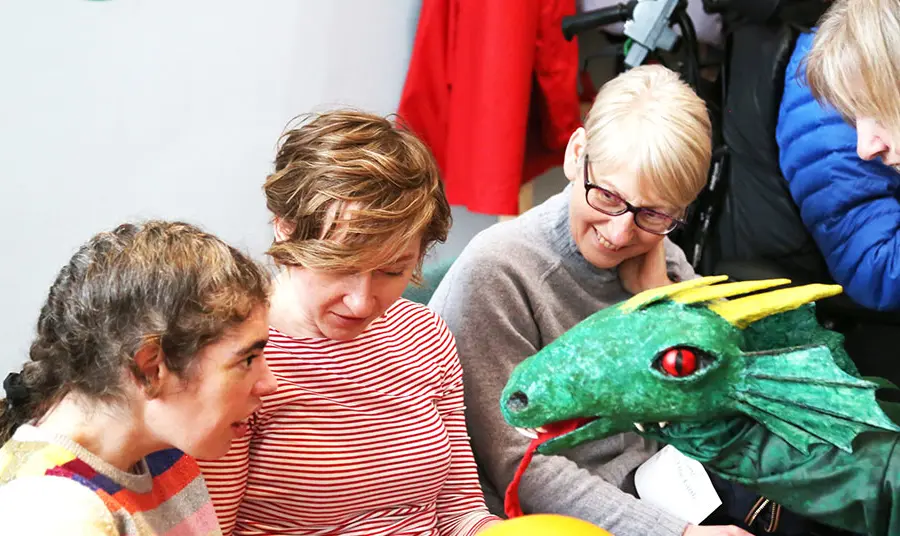 Young girl interacting with a dragon puppet during a PAMIS story telling session
