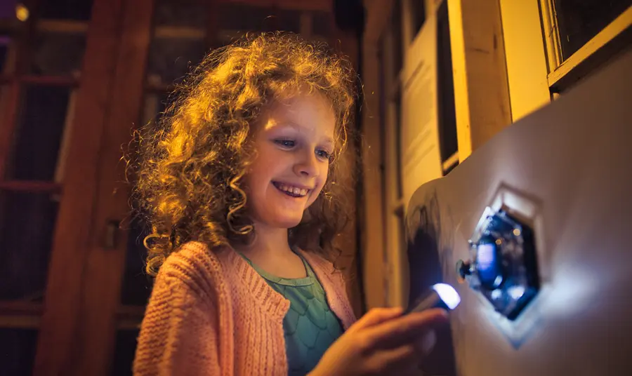 A child interacting with one of the Reimagining Reality exhibits and shining a light onto a shape on the wall.