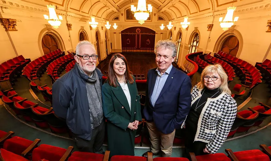 Four people stand in a grand hall