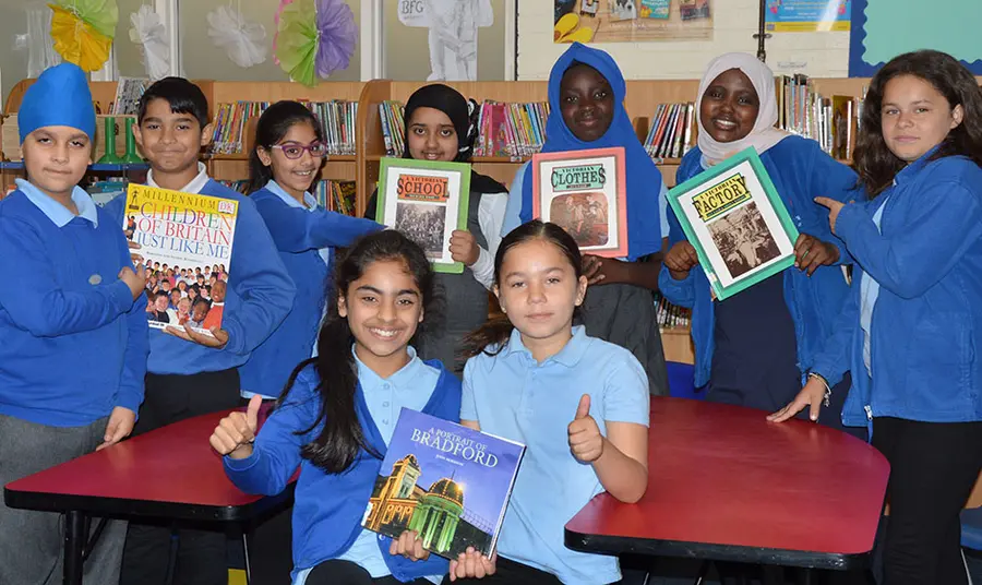 Group of children hold books whilst looking at the camera