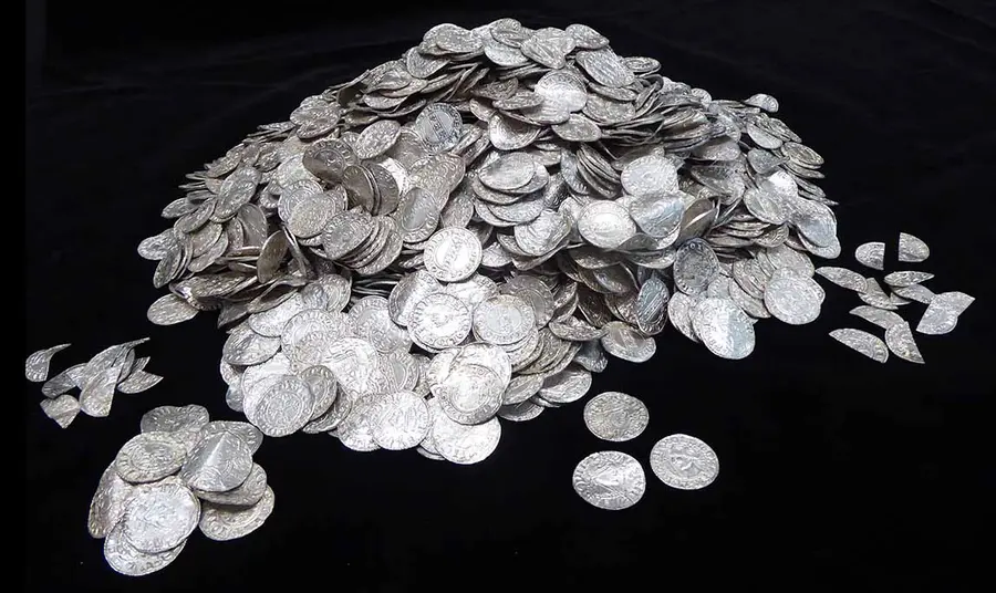 A large pile of silver coins on a black background