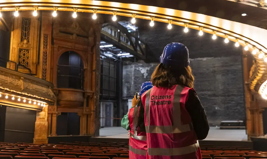 Two people in high vis jackets and hard hats explore the restored auditorium.