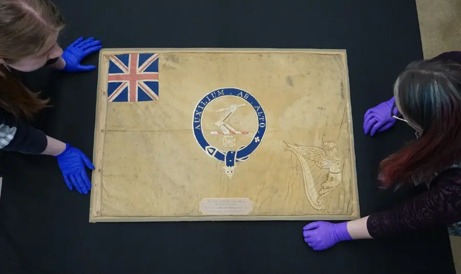 Conservators from the National Museum of the Royal Navy with the polar Kellett sledge flag