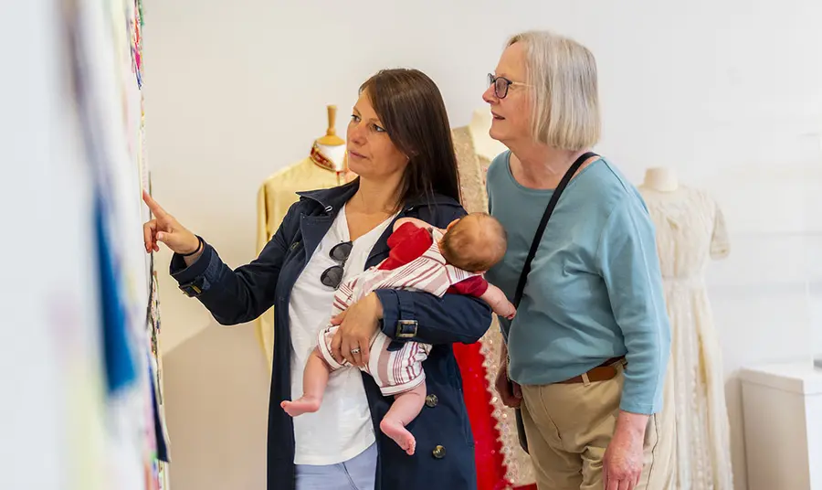 Two women and a baby look at museum display