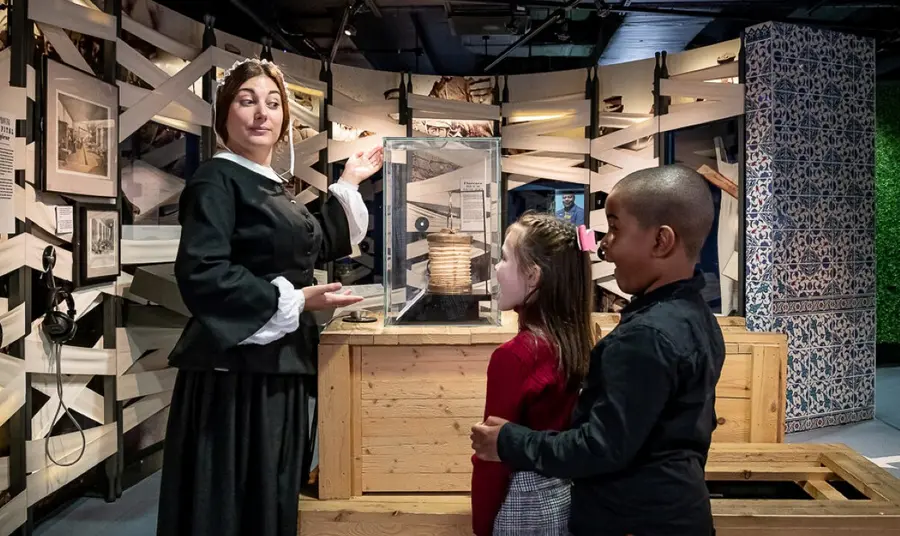 Two young visitors explore the Florence Nightingale Museum, meeting a member of museum staff dressed as Florence in Victorian nurses attire.