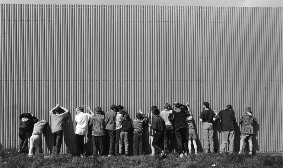 fpi-allianceavenue-glenbryn-northbelfast01.jpg A group of young boys sneak a view through gaps in a Belfast peace wall.