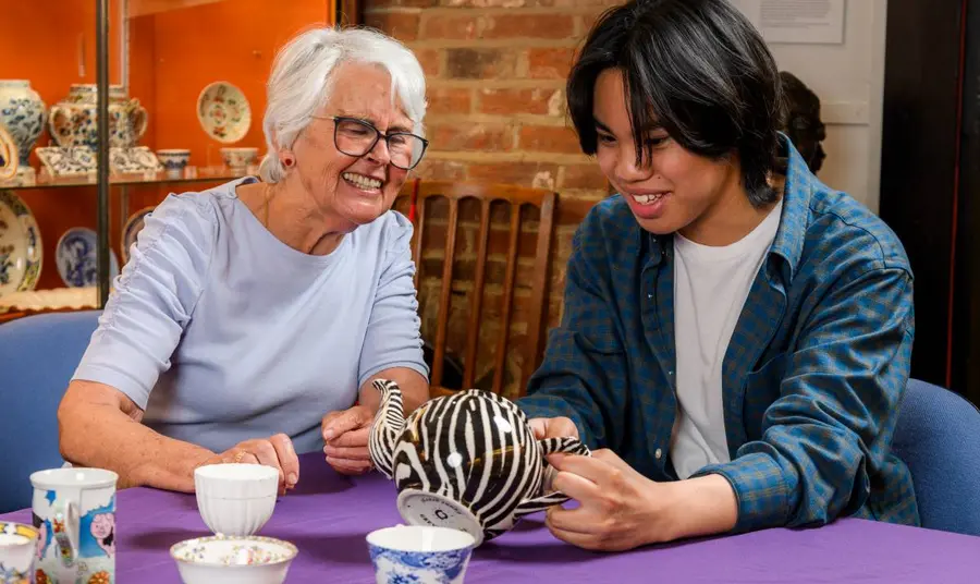 An older woman and a young adult man looking at ceramics