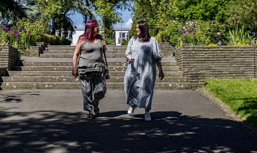 Two people talking and walking through a parkland