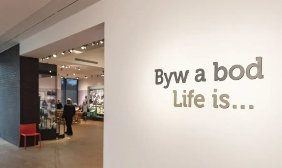 Text on a wall at a museum, displaying in both English and Welsh, which says 'Life is...'