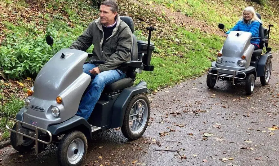 People driving mobility scooters through a park