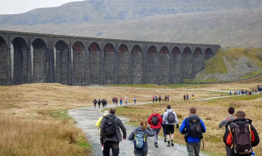 People walking along a country path by a viaduct in Yorkshire