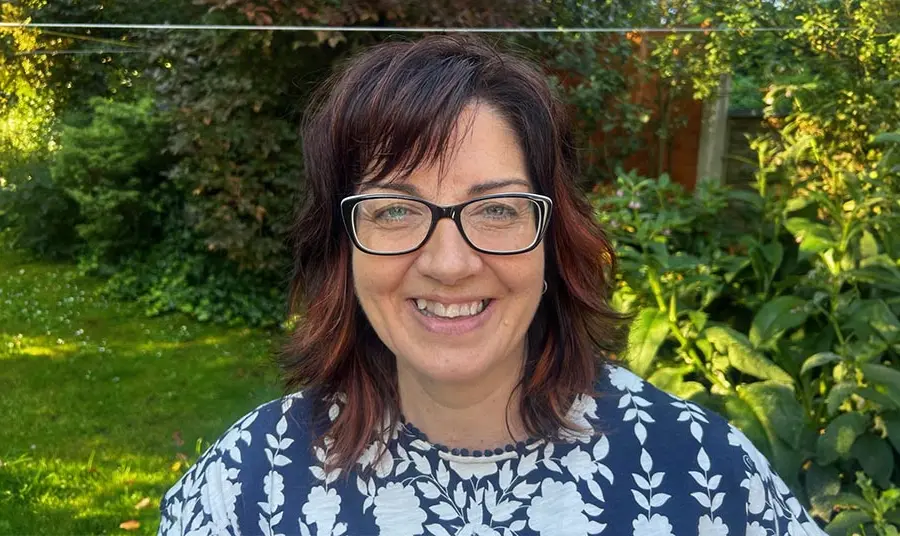 A woman with brown hair and glasses in a garden