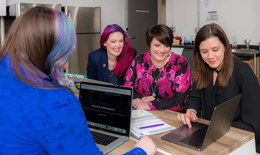 People working around a laptop. Photo Kylie Haulk on unsplash