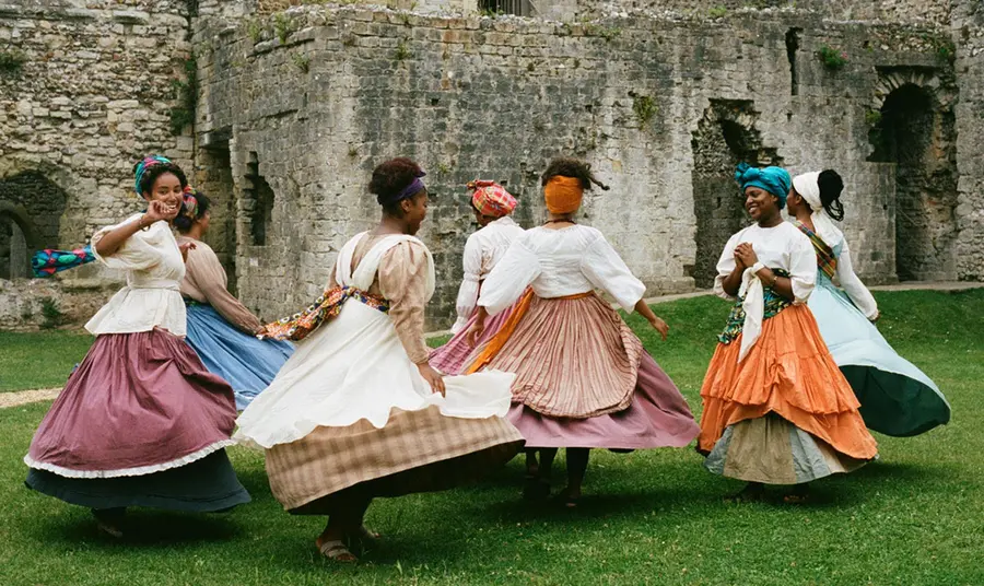 A group of women in period outfits dancing outside Porchester Castle.