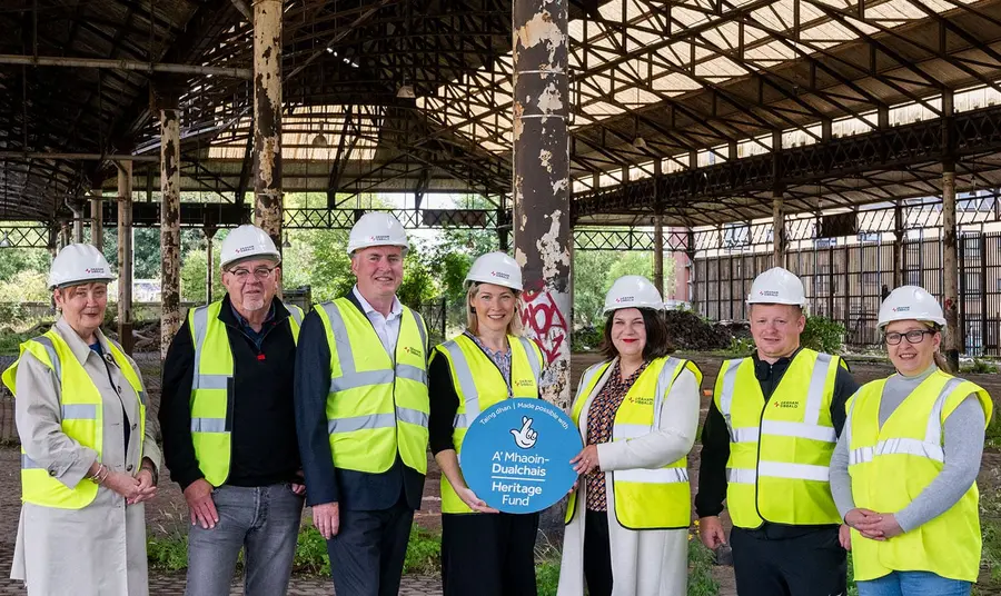 A group of people in hard hats and hi-vis jackets standing under Glasgow Meat Market's historic sheds.