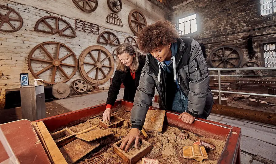 Two people do an activity in the foundry building, a large brick industrial building at the National Slate Museum in Wales