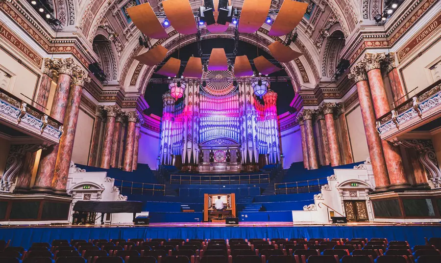 The interior of Leeds Town Hall with someone playing the organ on stage.