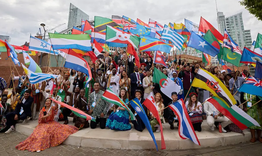 A large group of people sitting on a roundabout all holding flags for different countries of the world